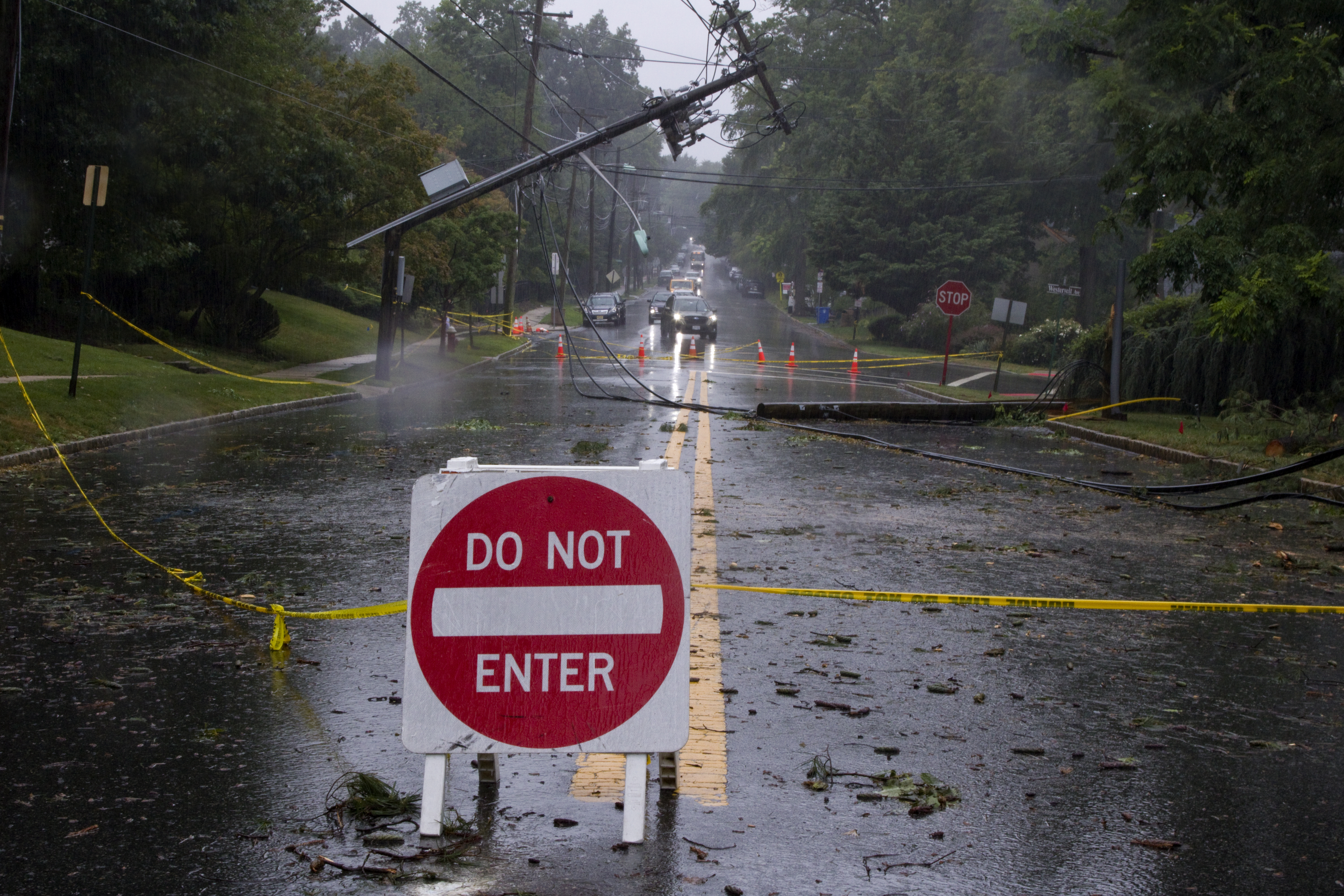 Storm damage with downed electrical pole and wires on residential street.